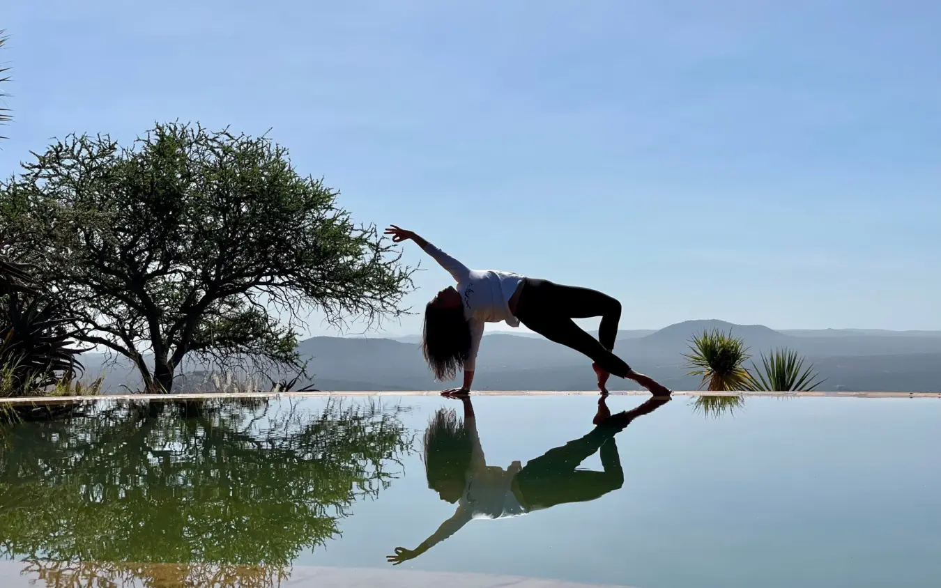 Woman practicing yoga on infinity pool deck at sunrise overlooking valley, Ol Malo House, Laikipia Highlands, Kenya