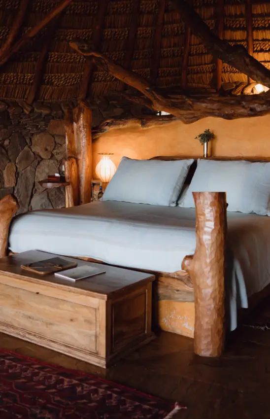 Rustic bedroom interior with wooden bed frame and thatched roof structure, Ol Malo House, Laikipia Highlands, Kenya
