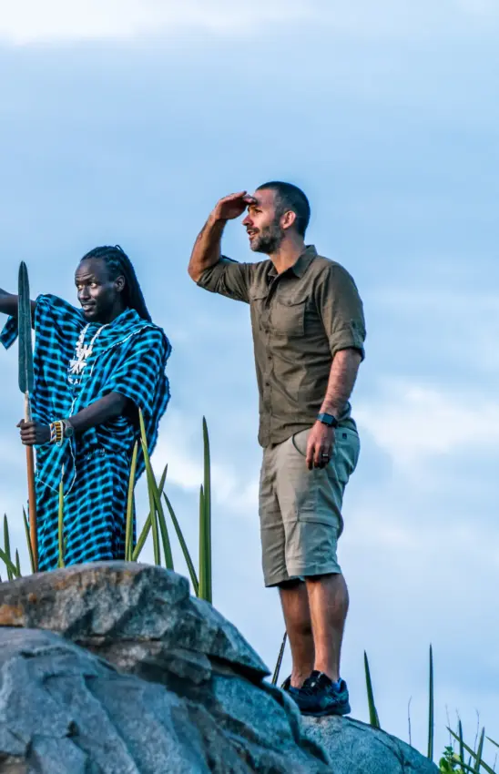 Local guide and tourist standing on rocky outcrop surveying landscape, Osonjoi Lodge, Ngorongoro Crater, Tanzania