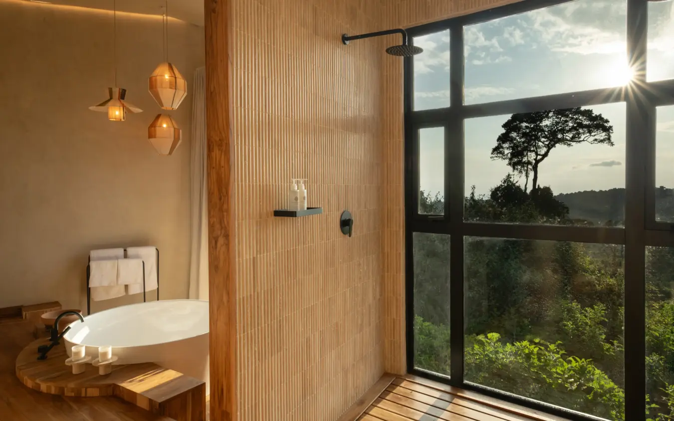 Luxury bathroom with soaking tub and woodland views through large windows, Osonjoi Lodge, Ngorongoro Crater, Tanzania