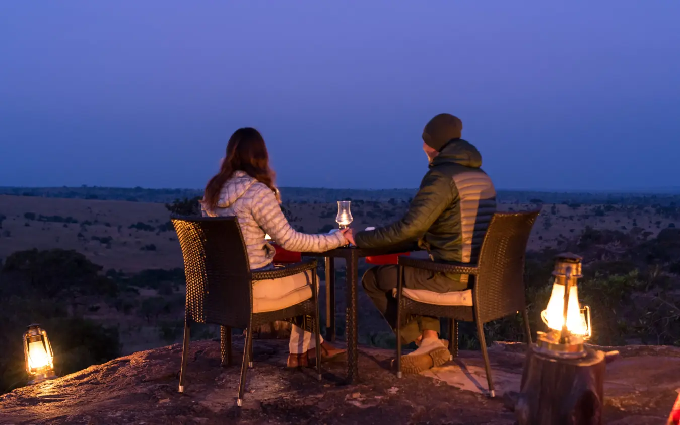 Couple toasting at sunset on elevated viewpoint overlooking savanna landscape, Osonjoi Lodge, Ngorongoro Crater, Tanzania