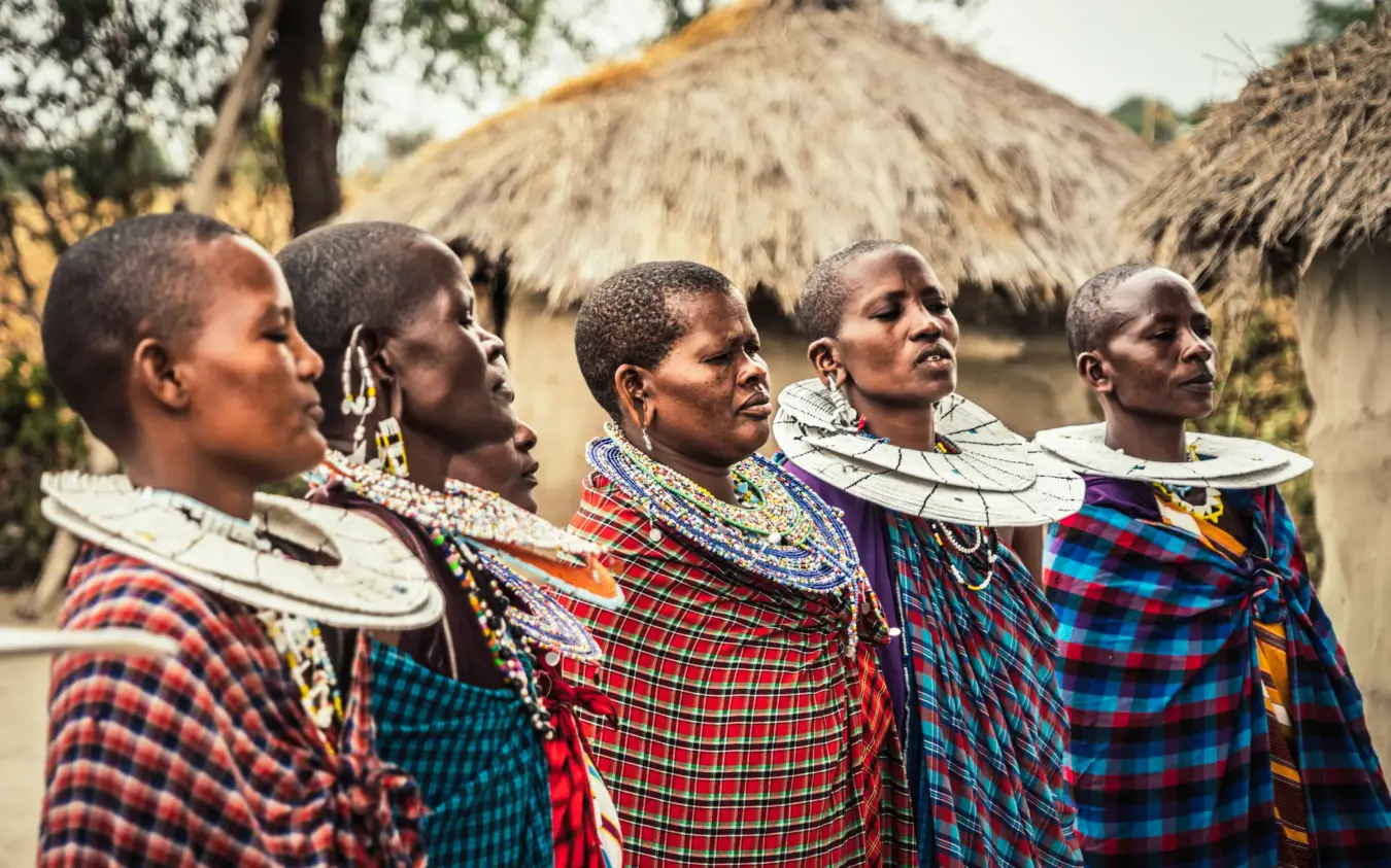 Maasai warriors in traditional beaded dress and cloth standing in village settlement, Osonjoi Lodge, Ngorongoro Crater, Tanzania