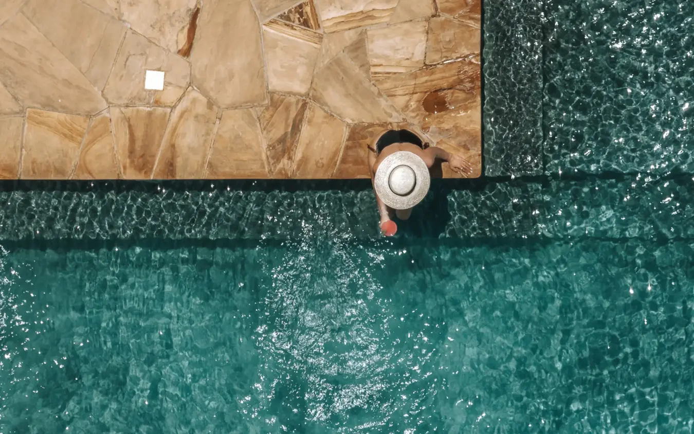 Person in hat sitting at pool edge on tiled deck, Osonjoi Lodge, Ngorongoro Crater, Tanzania