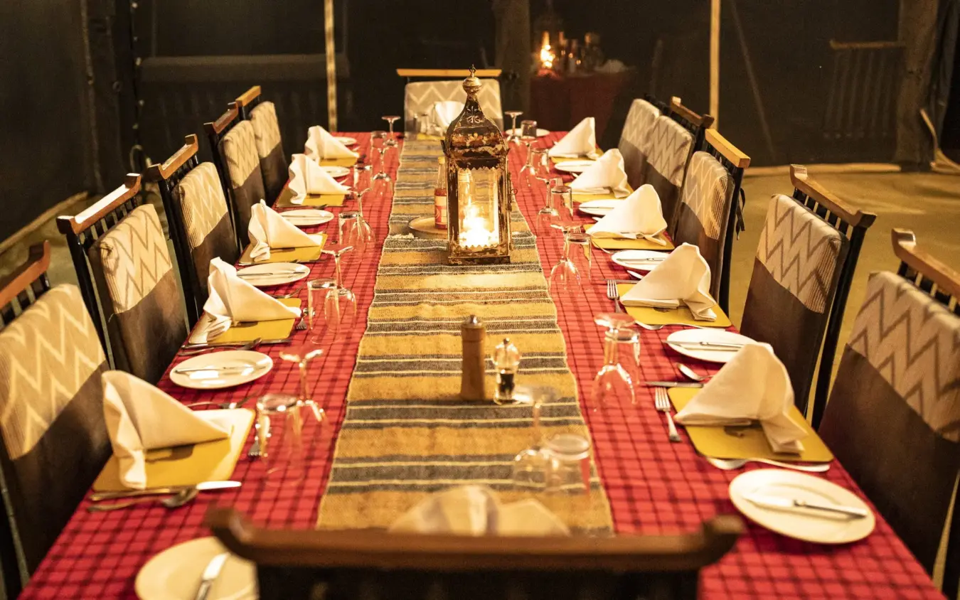 Formal dining table set for dinner service with red linens and candlelight, Porini Lion Camp, Maasai Mara, Kenya