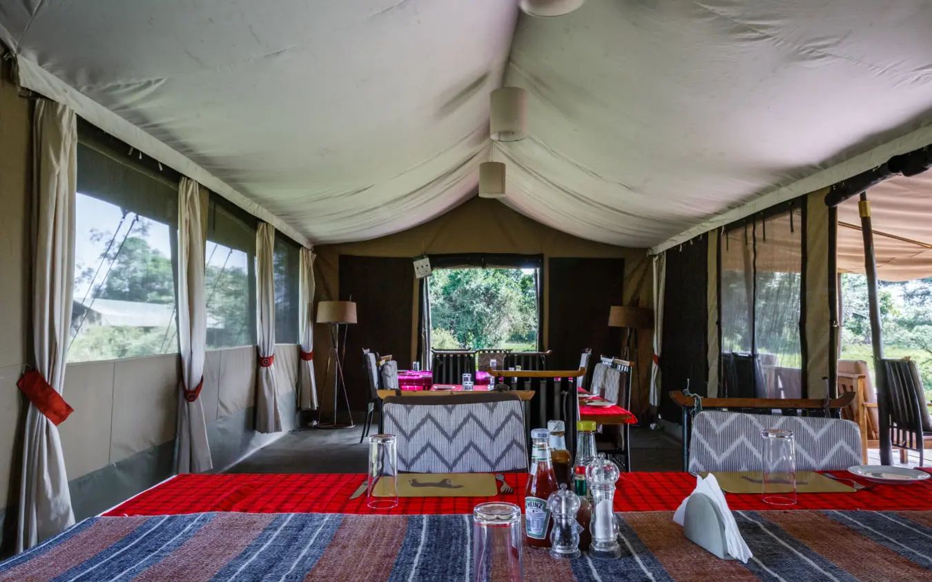 Safari tent interior with dining setup and savanna views, Porini Lion Camp, Maasai Mara, Kenya