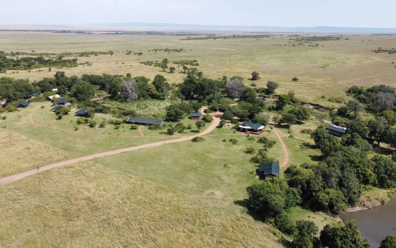Aerial view of riverside lodge compound nestled among trees in grassland, Porini Lion Camp, Maasai Mara, Kenya