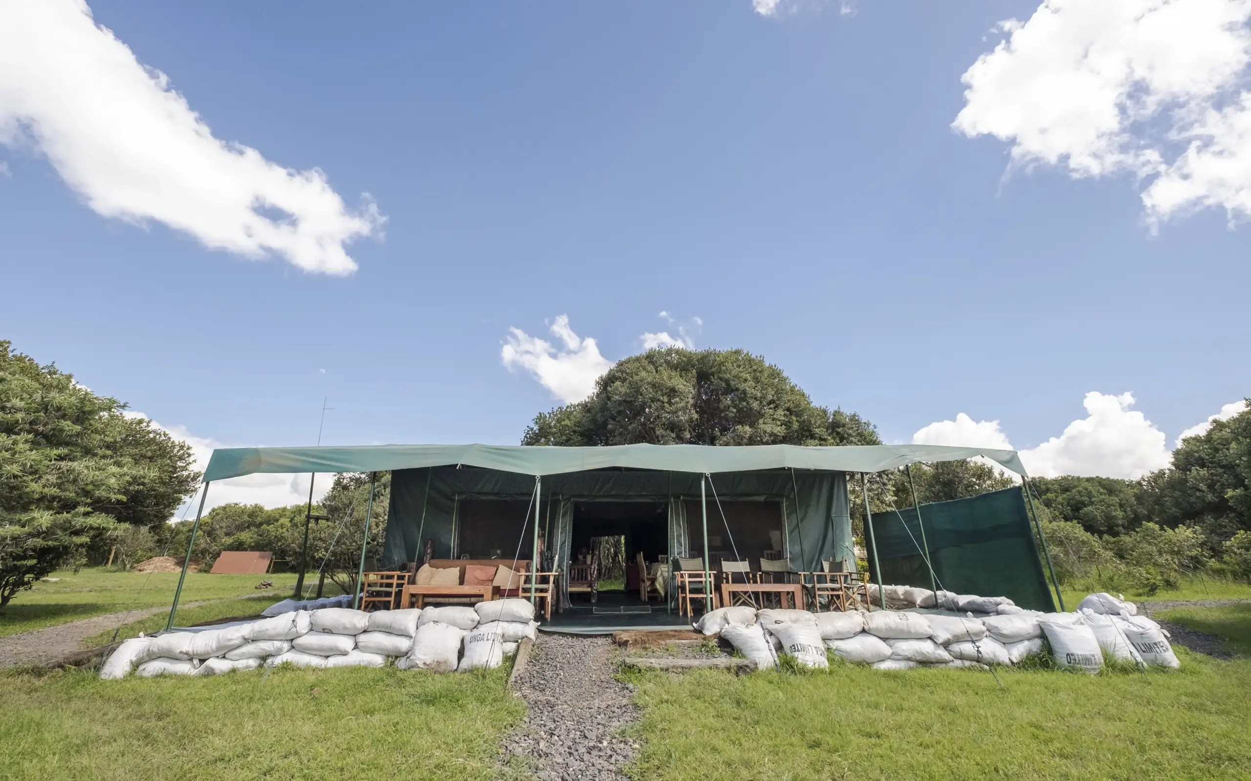 Luxury safari lodge tent with sandbag barriers and woodland backdrop, Porini Rhino Camp, Laikipia Highlands, Kenya