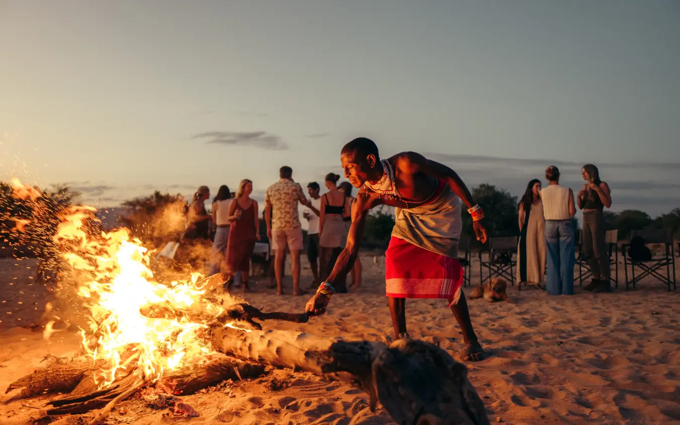 Group gathered around bonfire on beach at dusk, Reteti House, Northern Kenya, Kenya