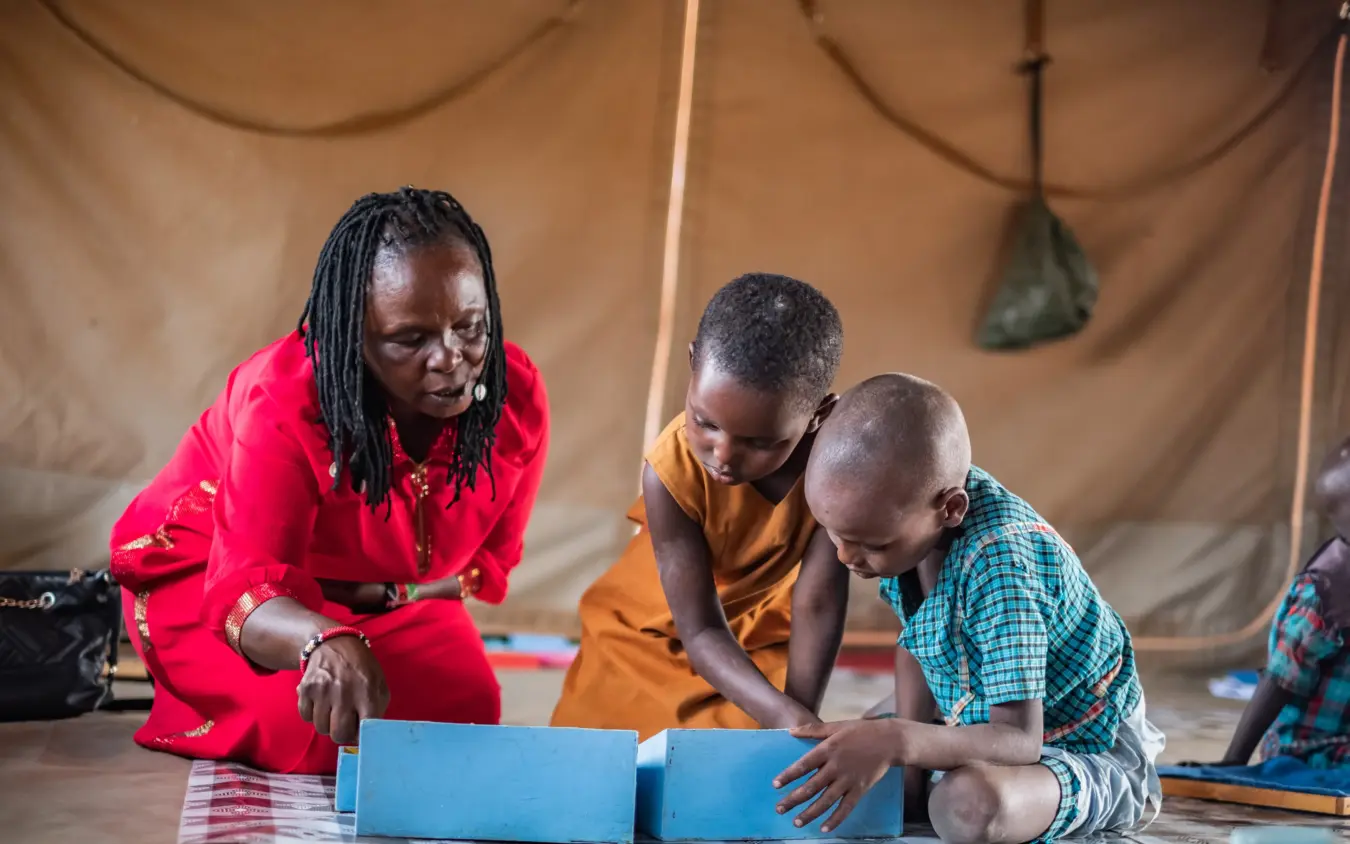 Woman and children reading together inside canvas tent, Reteti House, Northern Kenya, Kenya