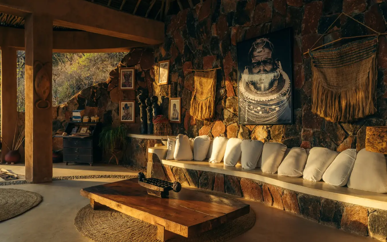 Rustic lounge interior with stone walls and cream cushioned seating, Reteti House, Northern Kenya, Kenya