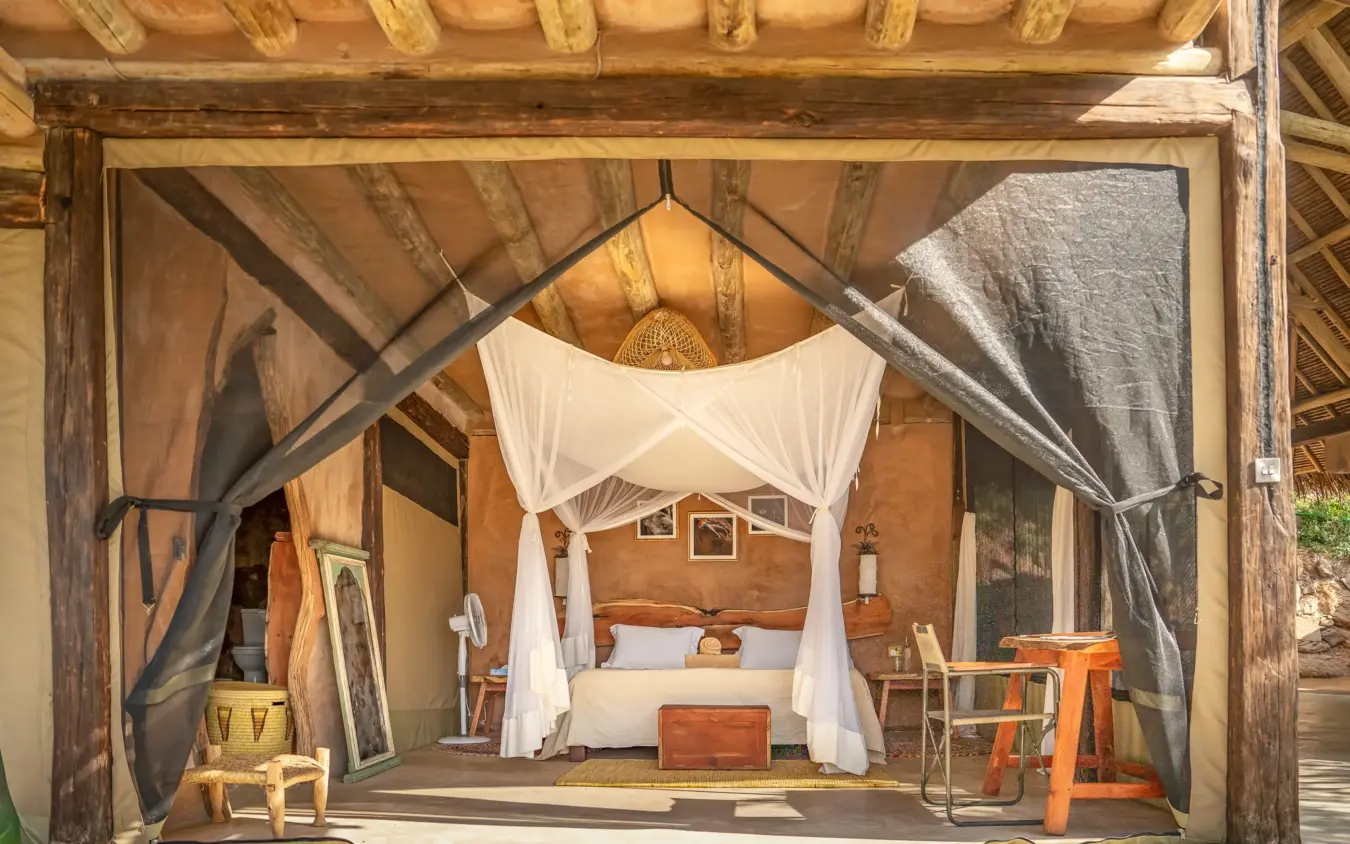 Canvas safari tent bedroom with draped four-poster bed and wooden beams, Reteti House, Northern Kenya, Kenya