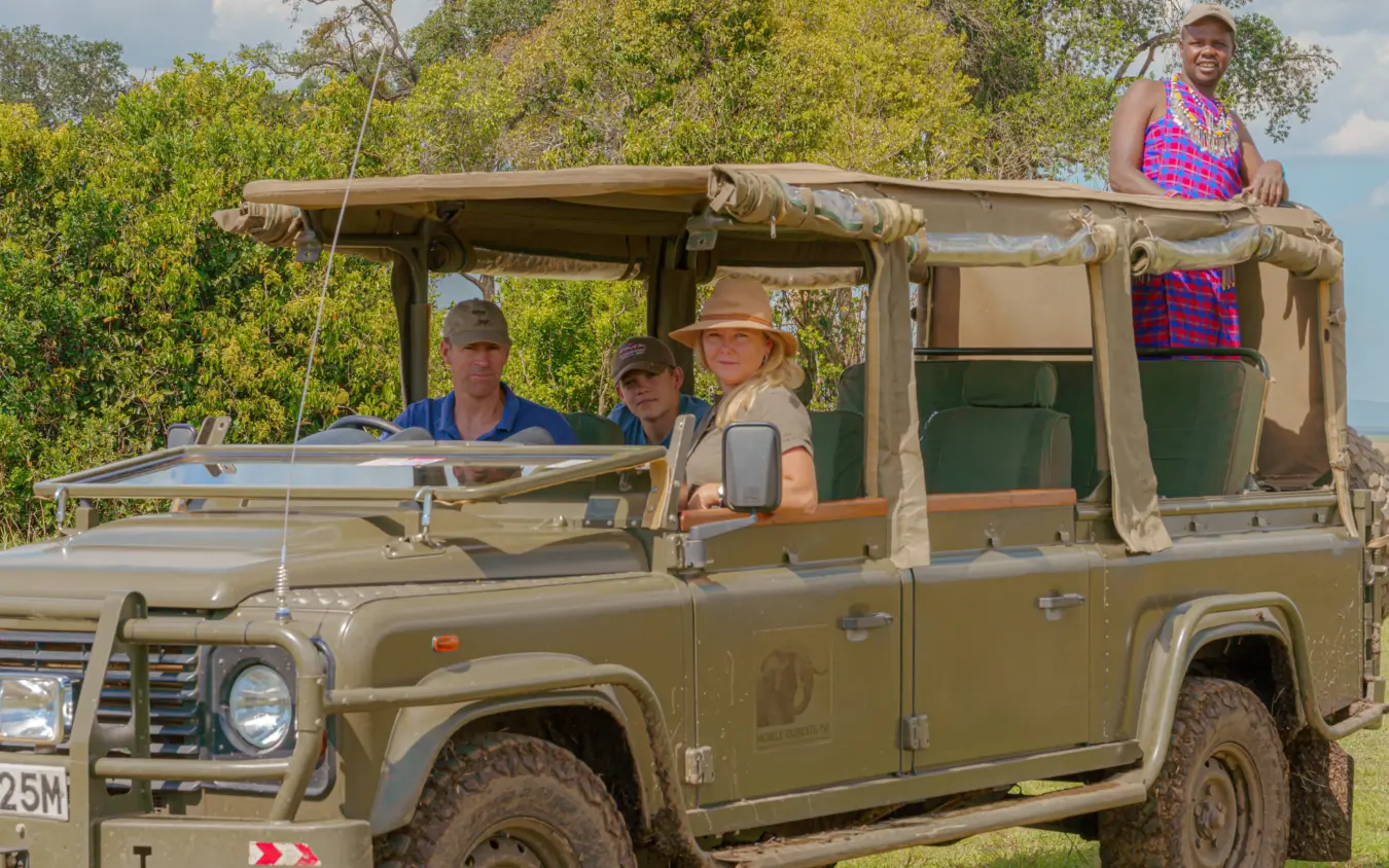 Safari vehicle with guides and guests on open-air game drive, Roca River Camp, Maasai Mara, Kenya