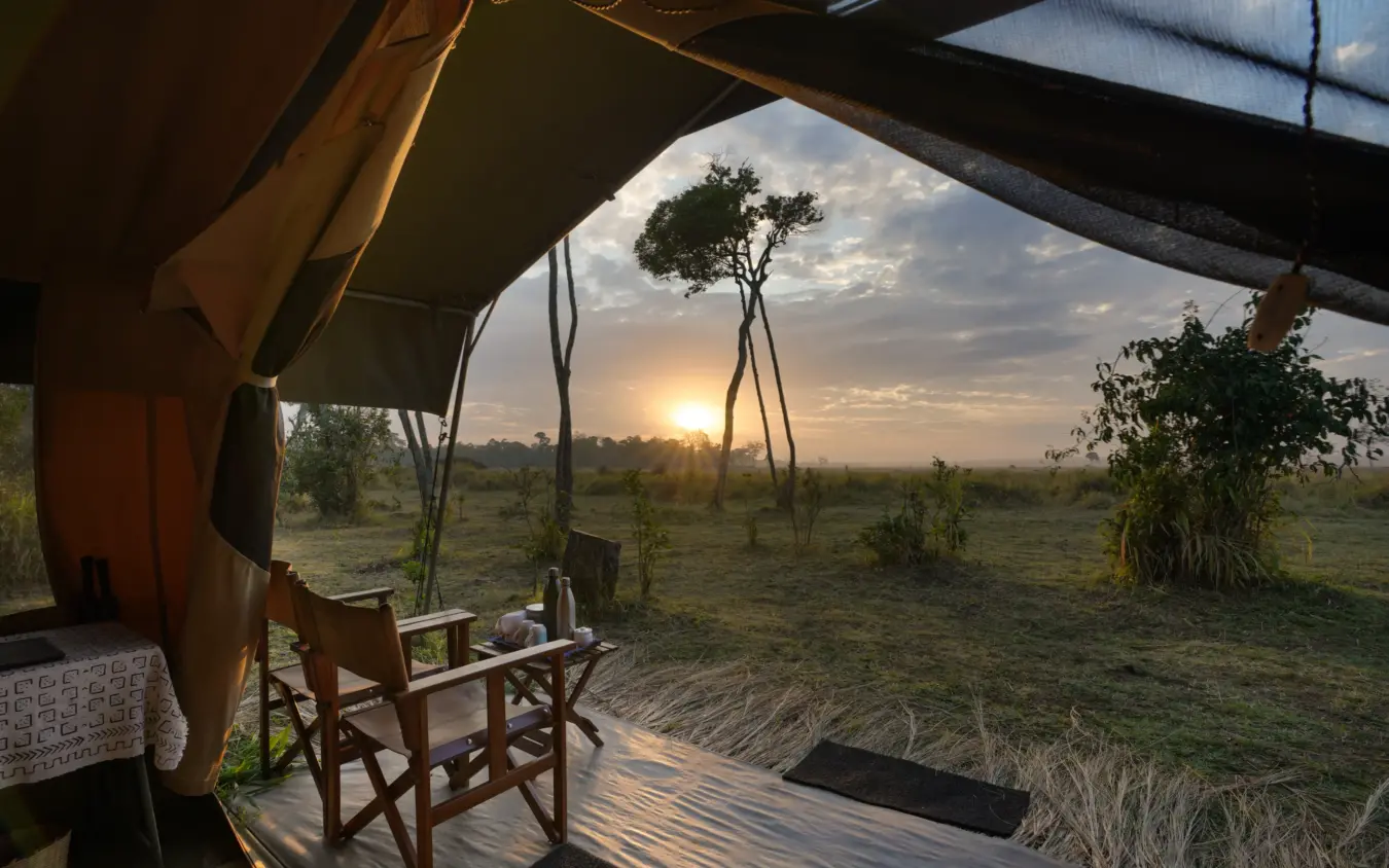 Safari tent interior at sunset overlooking grassland savanna, Roca River Camp, Maasai Mara, Kenya