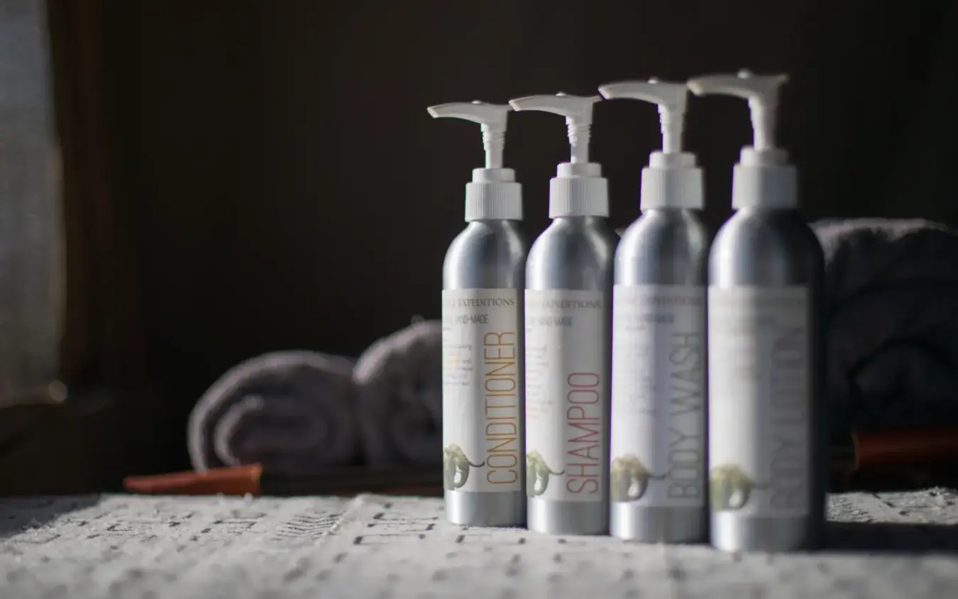 Luxury bathroom amenities with pump bottles and rolled towels on countertop, Roca River Camp, Maasai Mara, Kenya