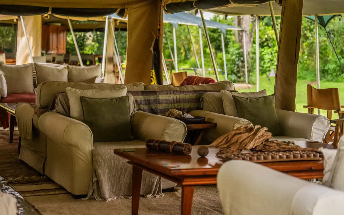 Luxury safari lounge tent with comfortable seating overlooking green landscape, Roca River Camp, Maasai Mara, Kenya