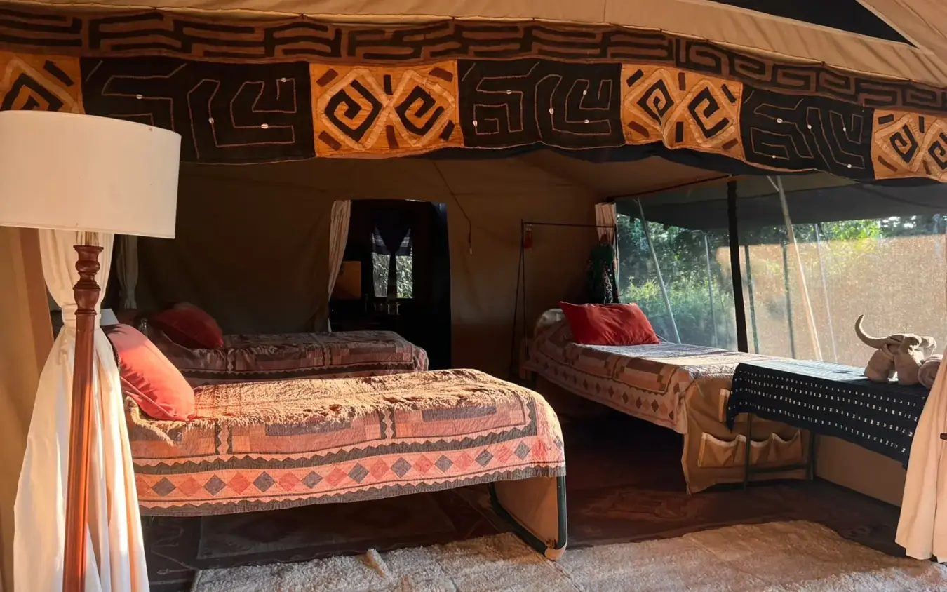Safari lodge tent interior with beds and geometric patterned textiles, Roca River Camp, Maasai Mara, Kenya