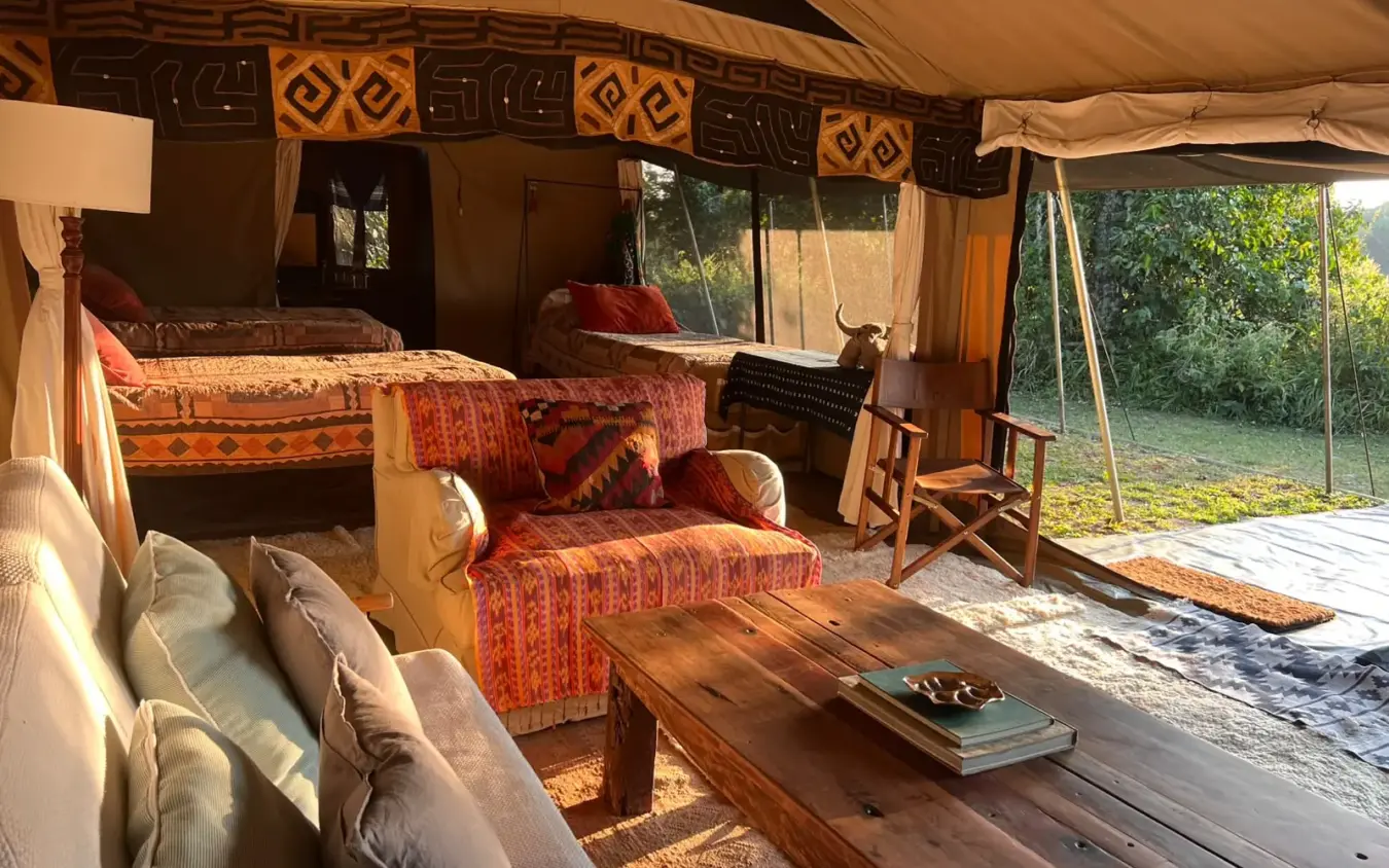 Luxury safari tent interior with beds and seating area overlooking woodland, Roca River Camp, Maasai Mara, Kenya