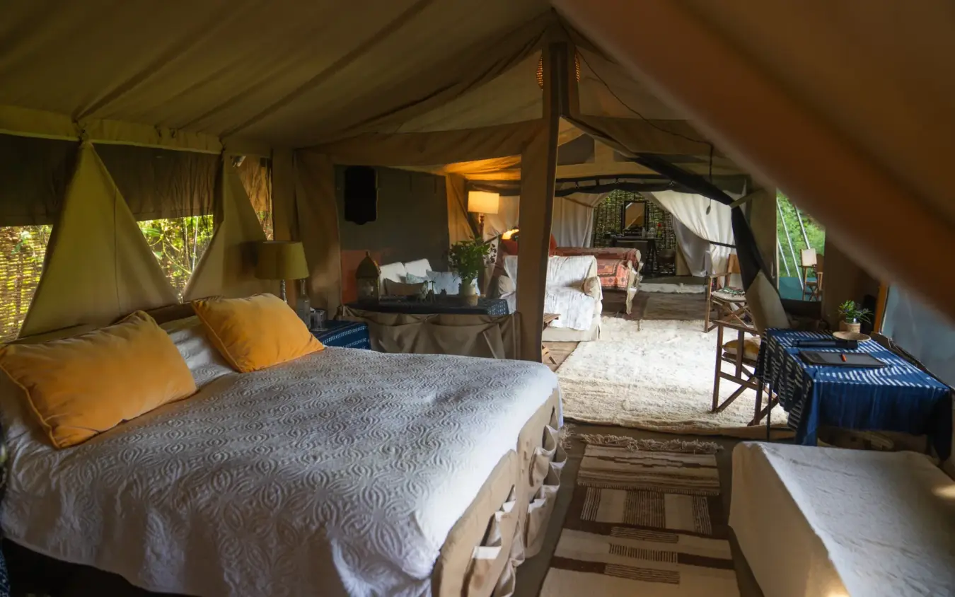 Luxury safari tent interior with king bed and canvas furnishings, Roca River Camp, Maasai Mara, Kenya