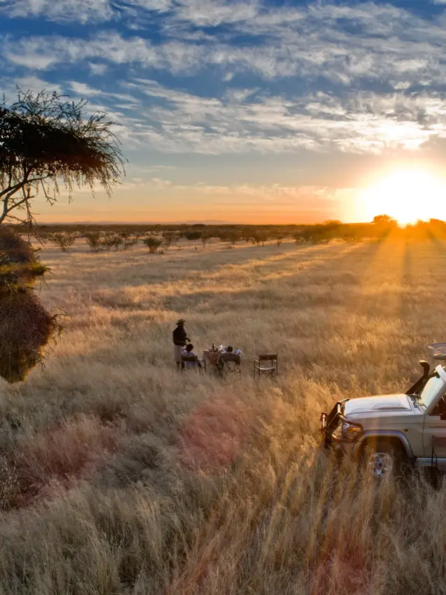 Sunset dining setup in open grassland with safari vehicle nearby, Safari House, Etosha National Park, Namibia