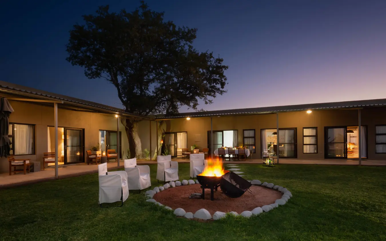 Luxury lodge courtyard with firepit and seated guests at dusk, Safari House, Etosha National Park, Namibia