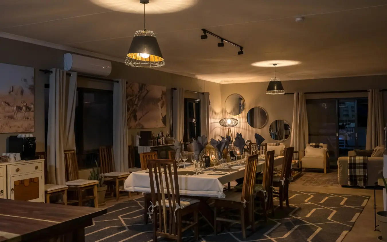 Dining room with round mirrors and pendant lighting at night, Safari House, Etosha National Park, Namibia