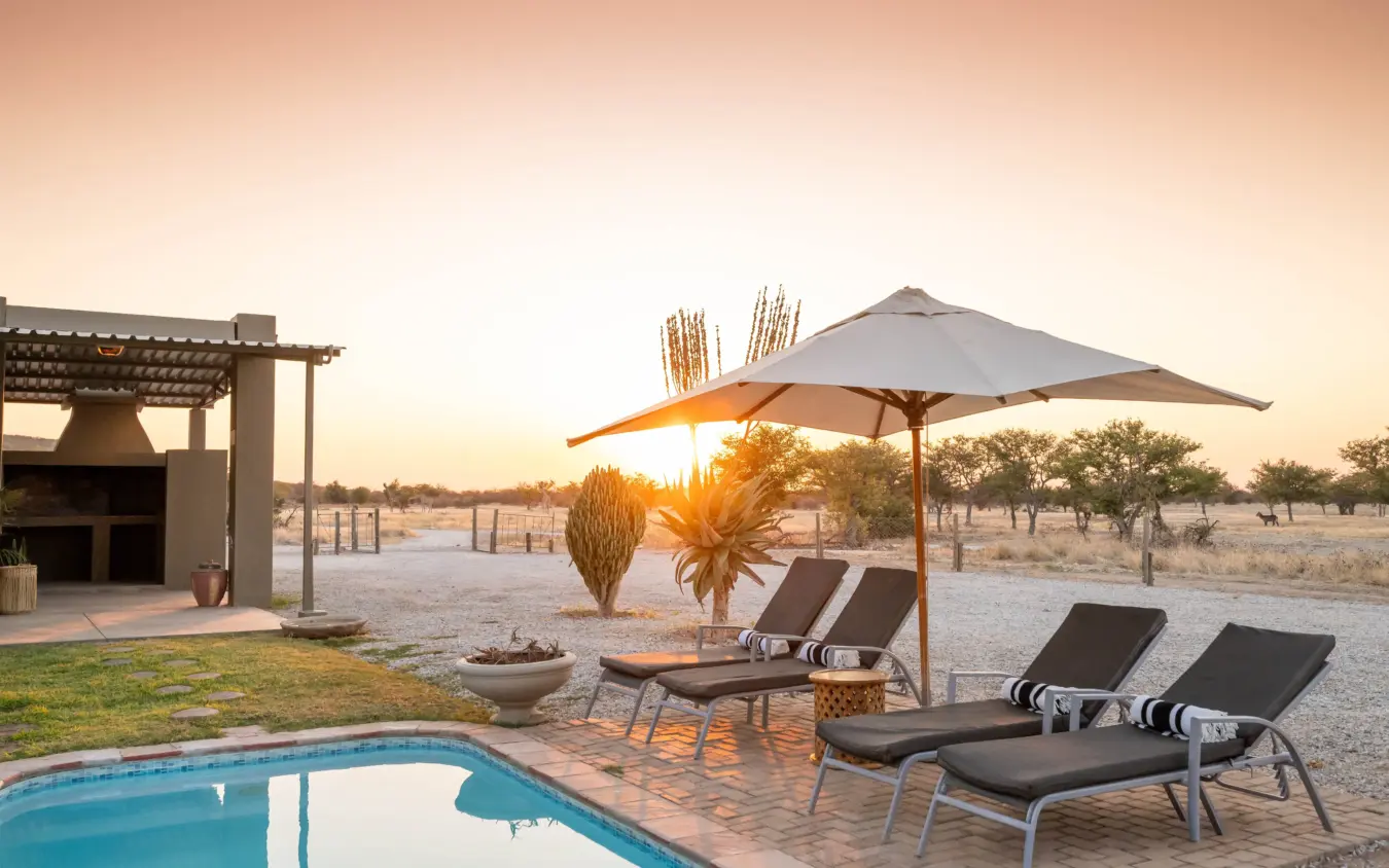 Luxury safari lodge pool and loungers at sunset overlooking vast savanna plains, Safari House, Etosha National Park, Namibia