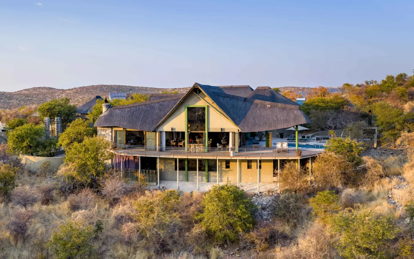 Elevated lodge with thatched roof overlooking brushland savanna landscape, Safarihoek Lodge, Etosha National Park, Namibia