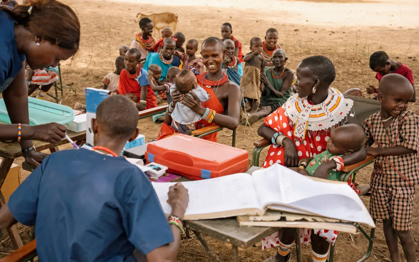 Educational outreach with children gathered around books and learning materials outdoors, Sarara Camp, Northern Kenya, Kenya