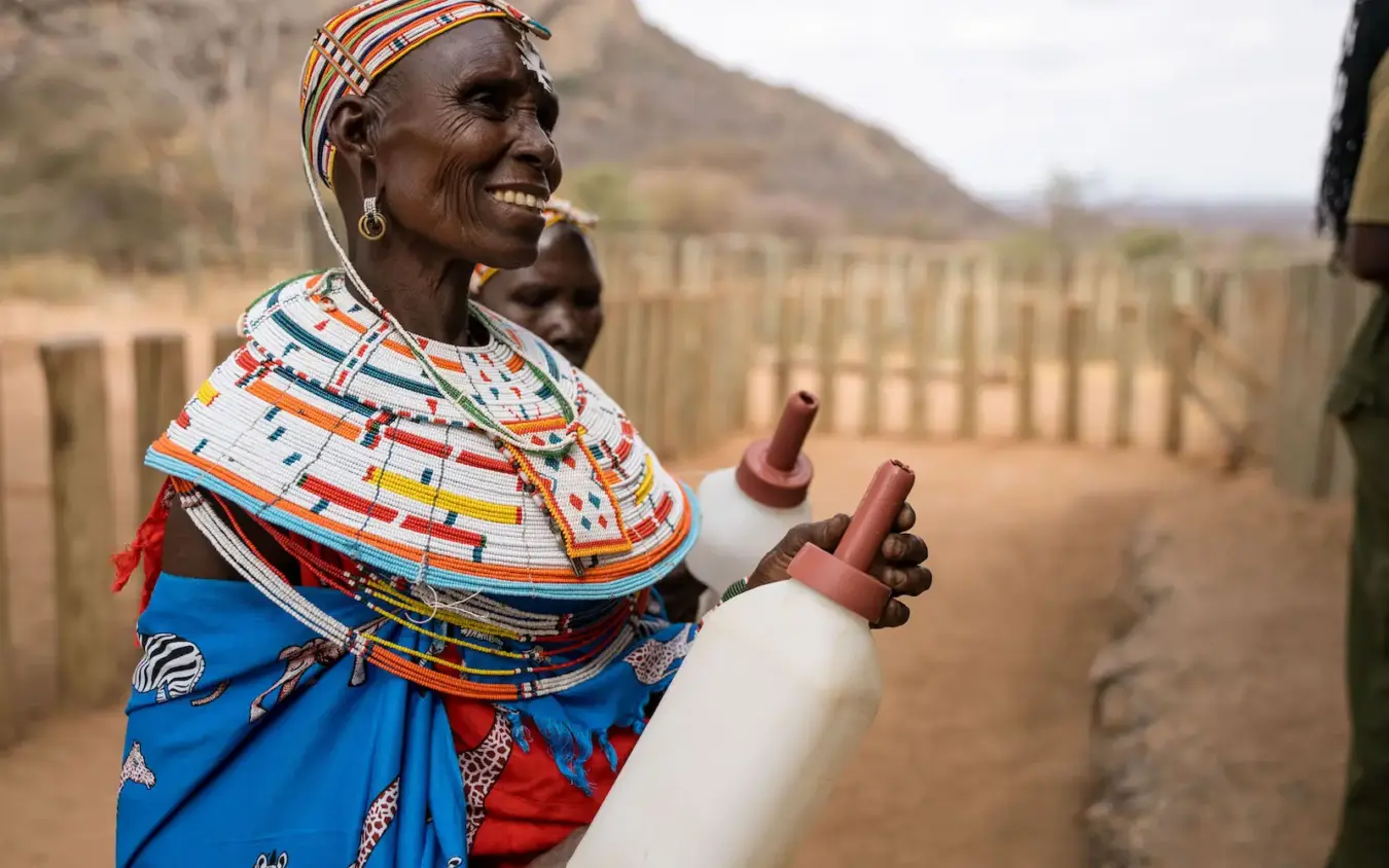 Maasai woman in traditional beaded attire holding water container in village, Sarara Camp, Northern Kenya, Kenya