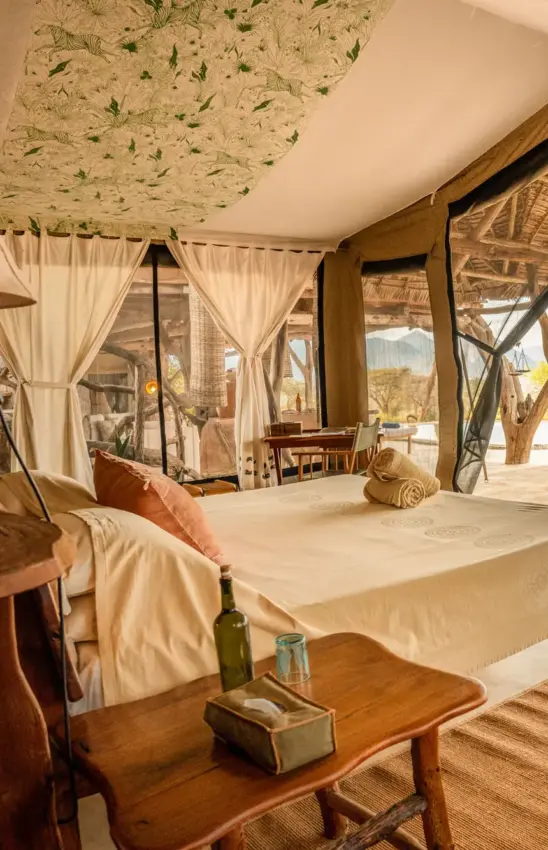 Luxury safari tent interior with canopy bed and savanna views through glass doors, Sarara Camp, Northern Kenya, Kenya