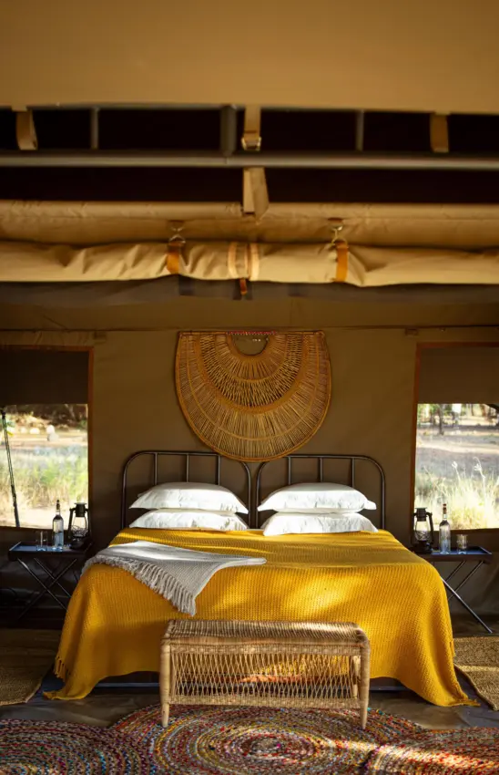 Luxury safari tent bedroom with yellow blanket and woven wall decoration, Sarara Wilderness, Northern Kenya, Kenya