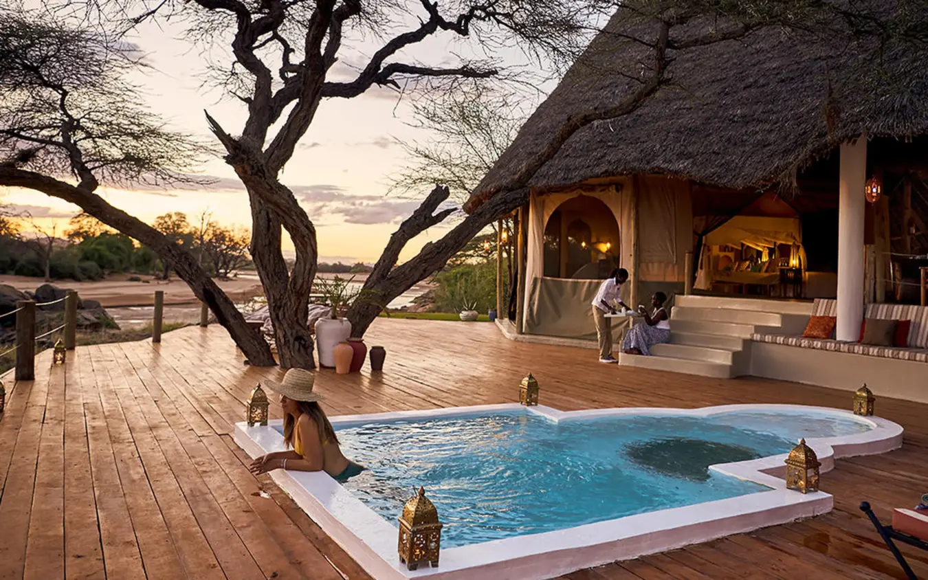 Riverside lodge pool at sunset with thatched roof bungalow, Sasaab, Samburu Reserve, Kenya