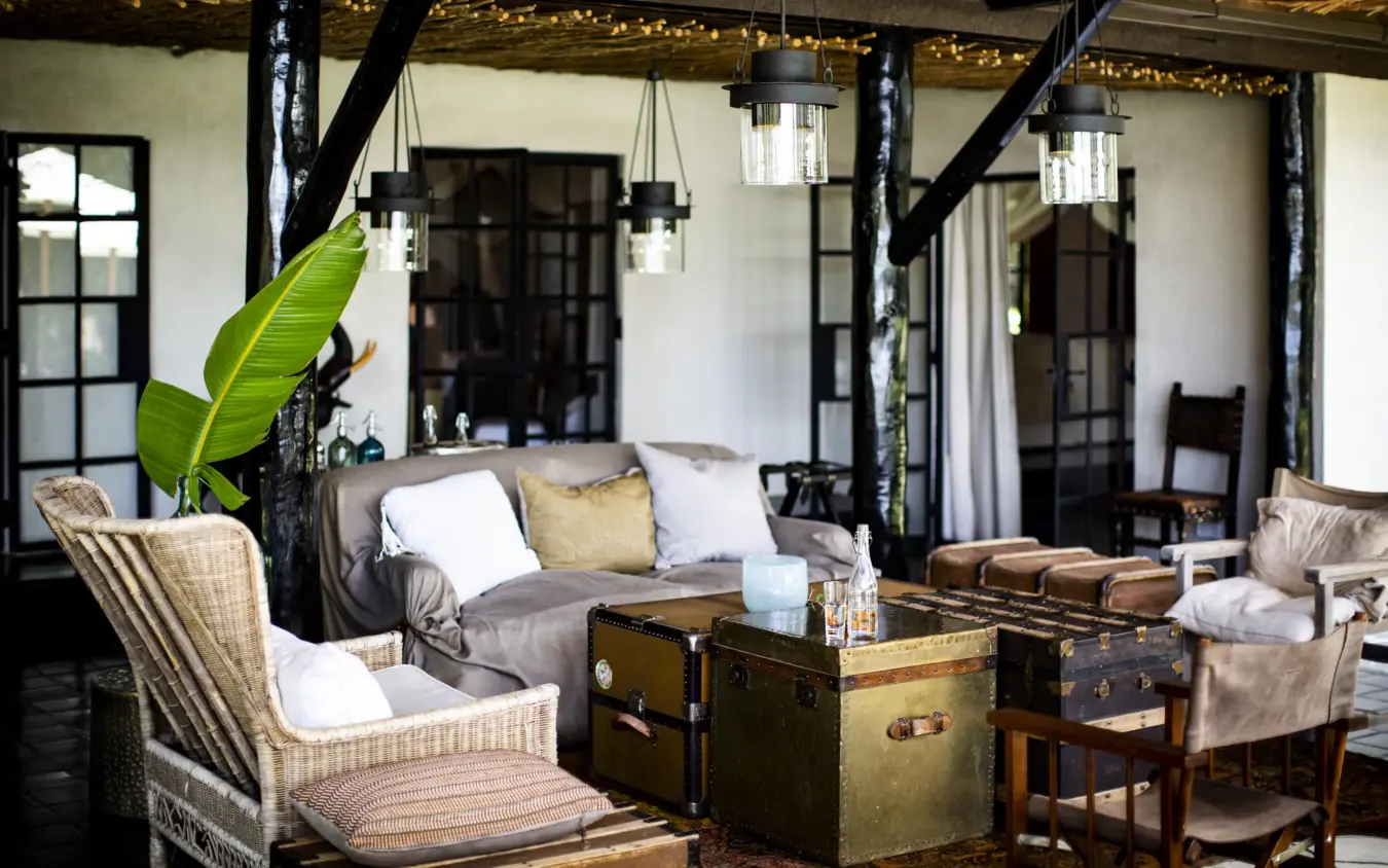 Open-air lounge with vintage trunks, wicker chairs, and pendant lighting, Segera, Laikipia Highlands, Kenya