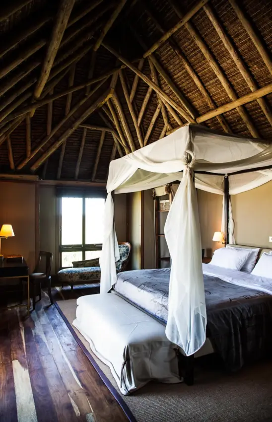 Luxury bedroom with four-poster bed and exposed wooden beam ceiling, Segera, Laikipia Highlands, Kenya