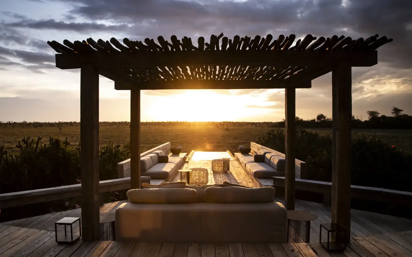 Pergola with daybed and fire pit overlooking vast grassland at sunset, Segera, Laikipia Highlands, Kenya