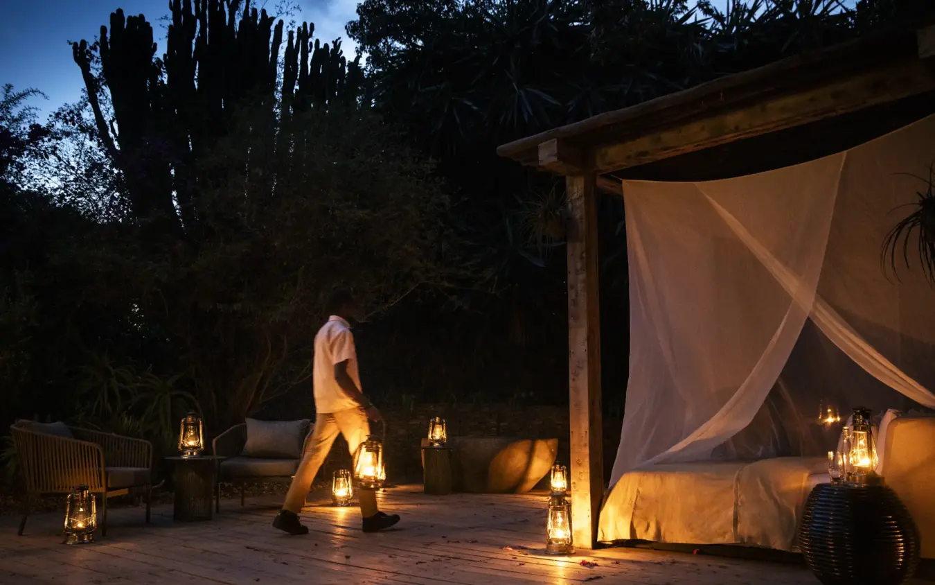 Outdoor bedroom with canopy bed and lanterns at night under stars, Segera, Laikipia Highlands, Kenya