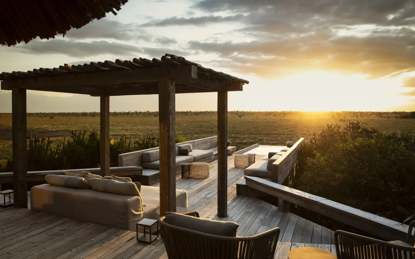 Wooden deck with lounge seating and pergola overlooking savanna at sunset, Segera, Laikipia Highlands, Kenya