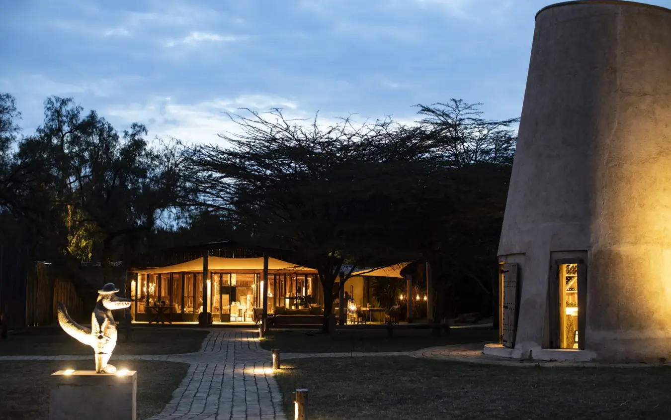Illuminated lodge pavilion with modern architecture at dusk in natural landscape, Segera, Laikipia Highlands, Kenya