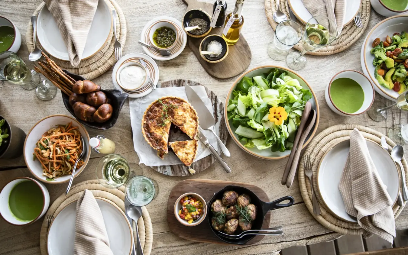 Overhead view of outdoor dining table set for multiple guests with fresh salads and grilled meats, Segera, Laikipia Highlands, Kenya