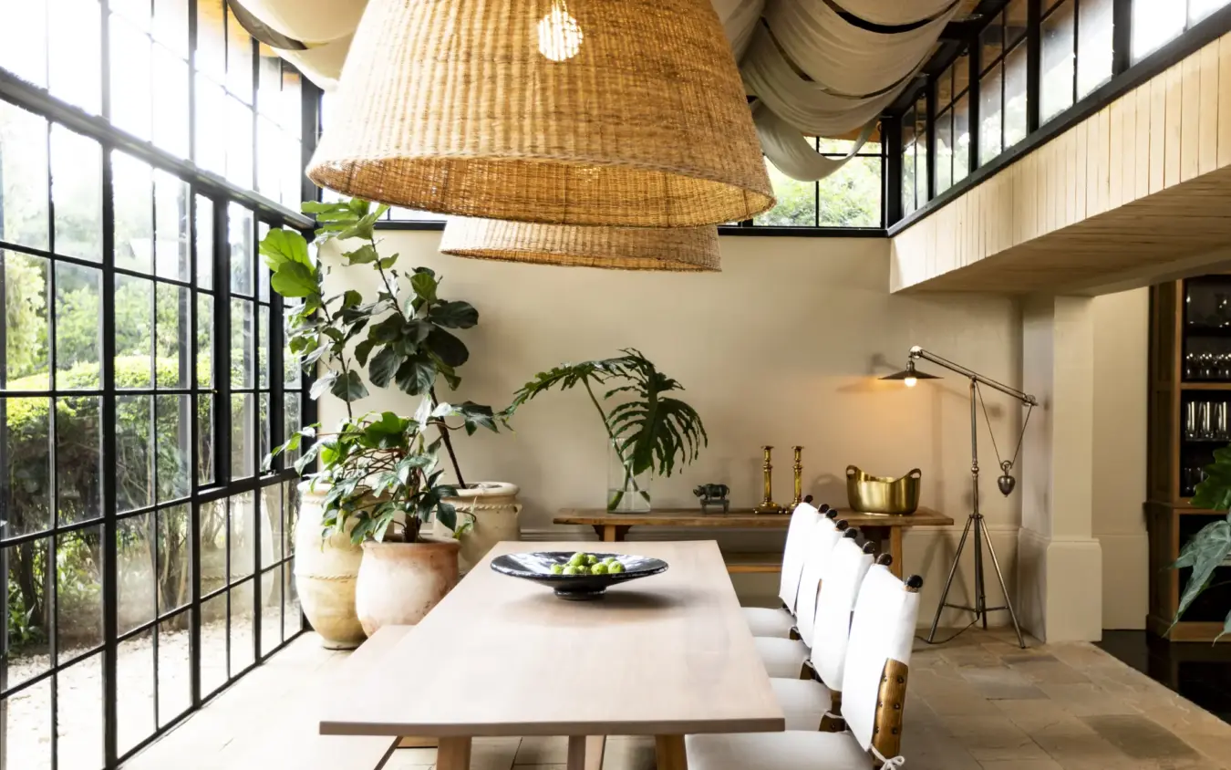 Modern dining room with rattan pendant lights and indoor plants, Segera, Laikipia Highlands, Kenya