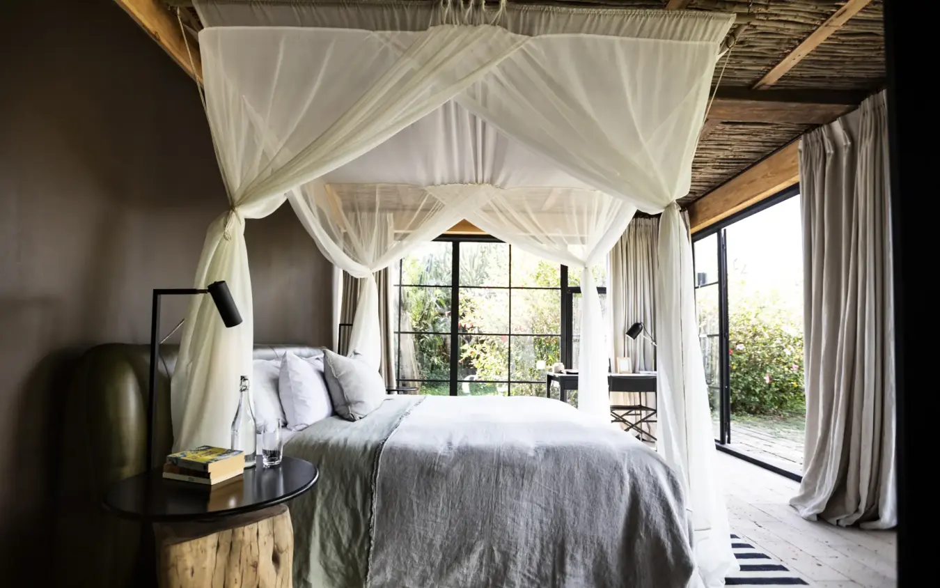 Canopy bed with sheer curtains in open-sided bedroom pavilion, Segera, Laikipia Highlands, Kenya