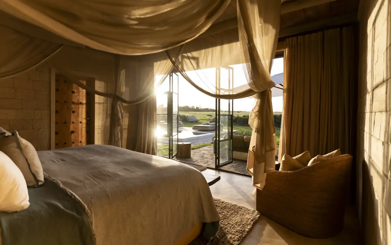 Luxury bedroom with sheer canopy overlooking river landscape at sunset, Segera, Laikipia Highlands, Kenya