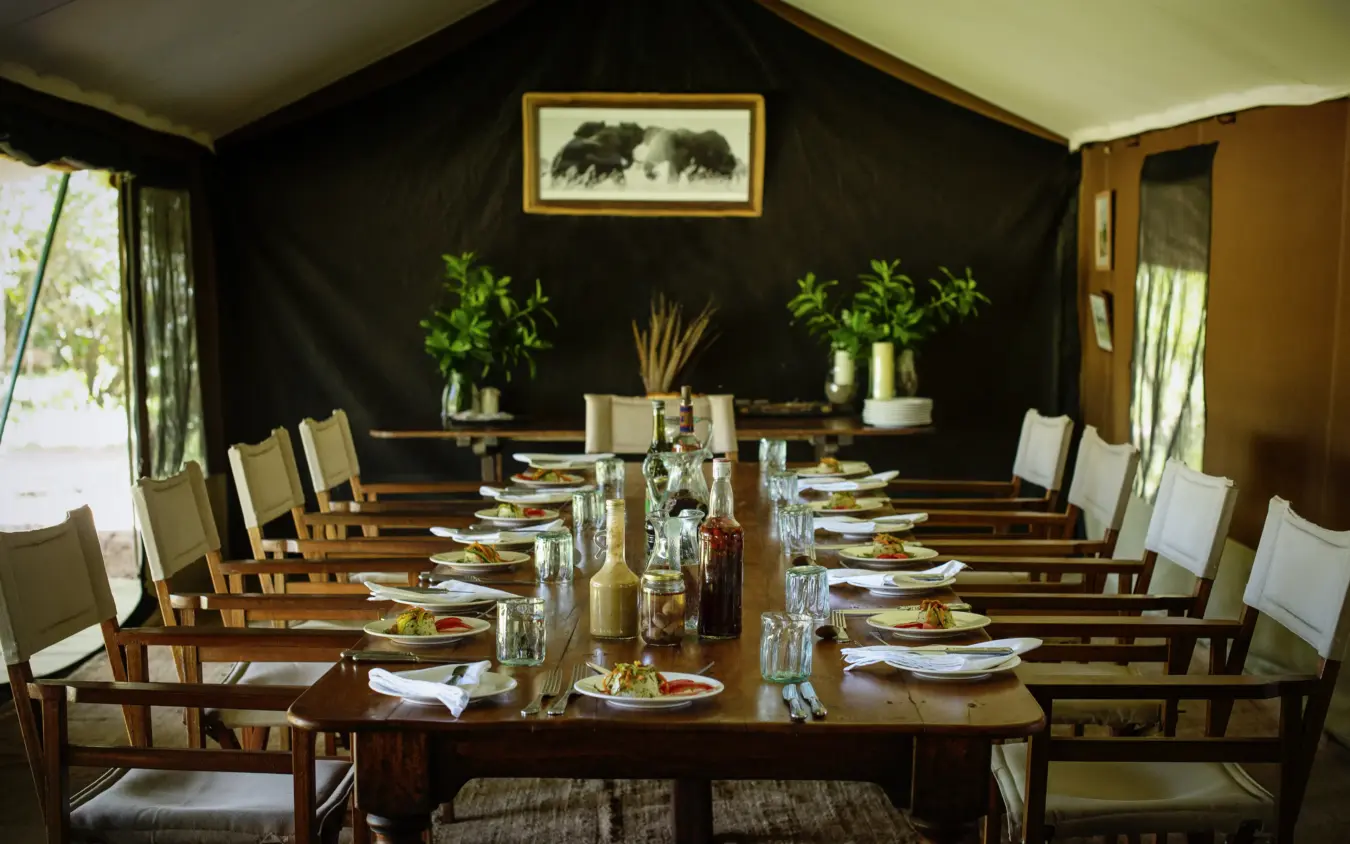 Elegant dining tent interior with long table set for service, Serian Nkorombo, Maasai Mara, Kenya