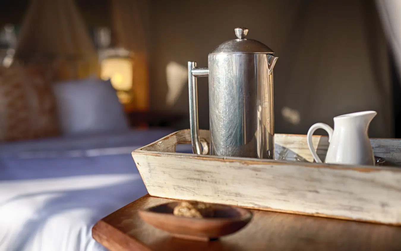 In-room coffee service tray with metal pot and white pitcher on wooden table, Serian Serengeti Mobile Kusini, Serengeti National Park, Tanzania