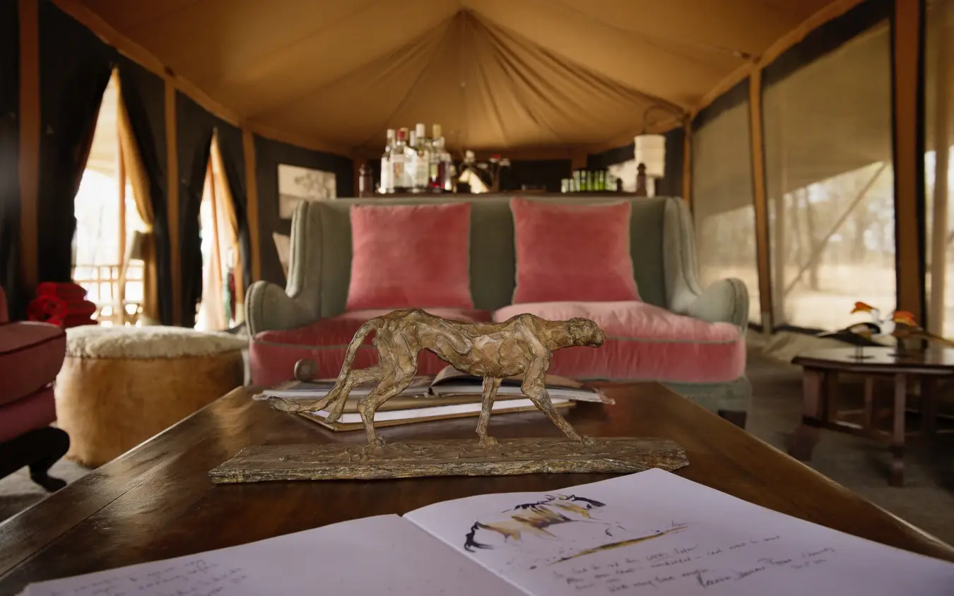 Luxury safari tent interior with animal sculpture on desk and pink velvet seating, Serian Serengeti Mobile Kusini, Serengeti National Park, Tanzania