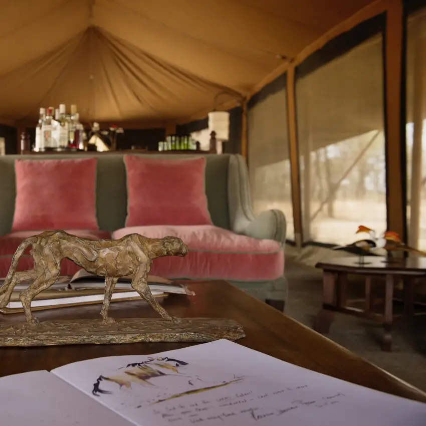 Luxury safari tent interior with animal sculpture on desk and pink velvet seating, Serian Serengeti Mobile Kusini, Serengeti National Park, Tanzania