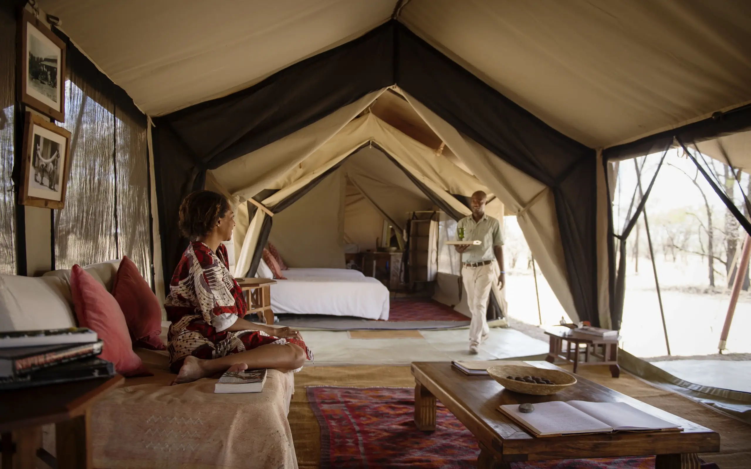 Luxury safari tent interior with guest seated on cushioned seating area, Serian Serengeti Mobile Kusini, Serengeti National Park, Tanzania