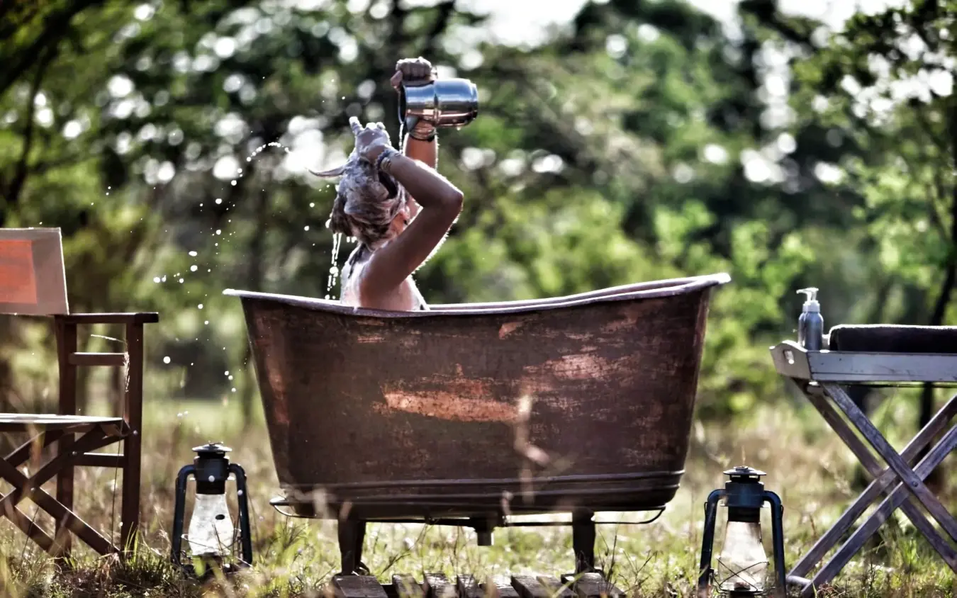 Man bathing in outdoor tub surrounded by natural landscape, Serian Serengeti South, Serengeti National Park, Tanzania