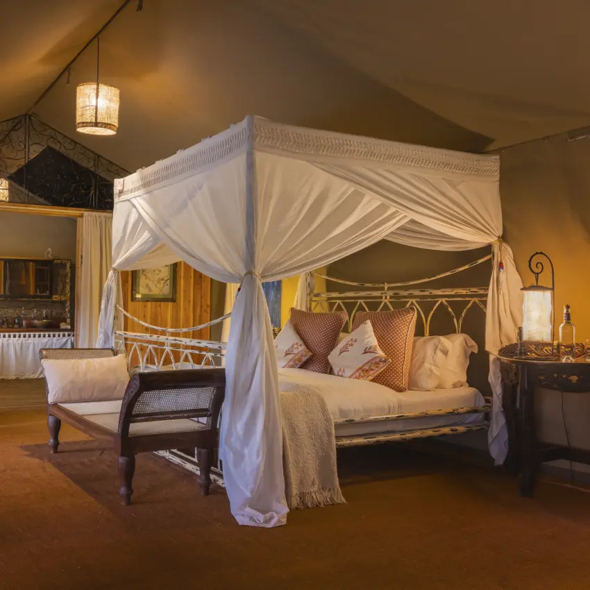 Luxury canopy bed with flowing white drapes in safari lodge bedroom, Serian “The Original”, Maasai Mara, Kenya