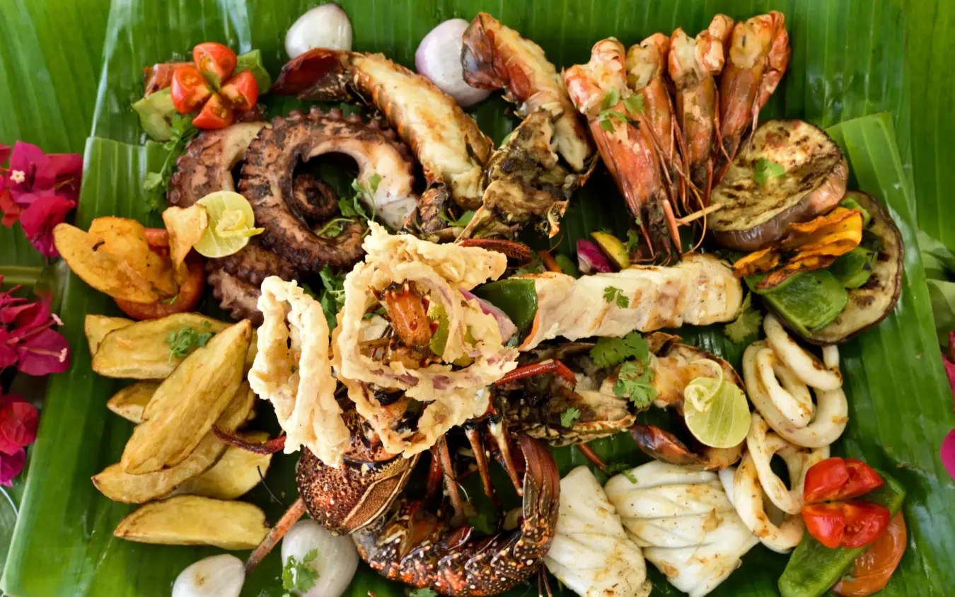 Grilled seafood and fried plantains plated on banana leaf, Sharazad Boutique Hotel, Zanzibar & Pemba, Tanzania
